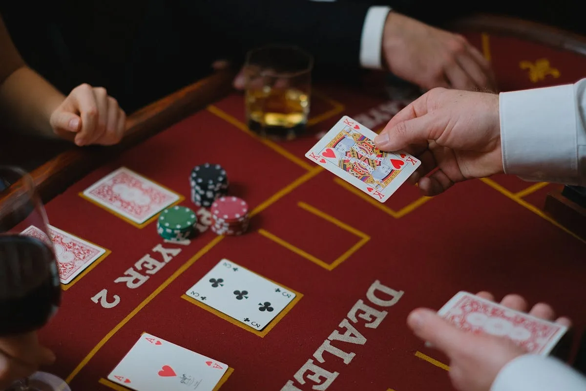 Table de casino rouge avec la mention DEALER et un roi de cœur tenu en main — argot casino anglais