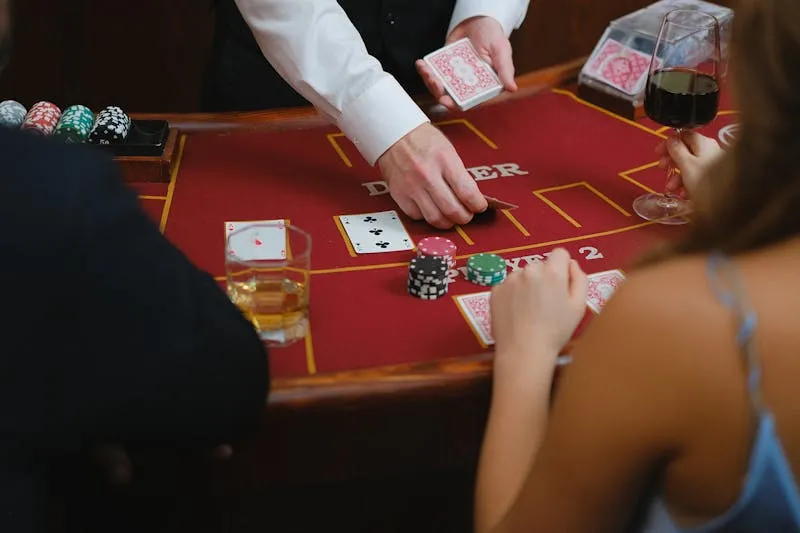 Dealer de casino distribuant les cartes sur table rouge — hiérarchie casino dealer pit boss en anglais